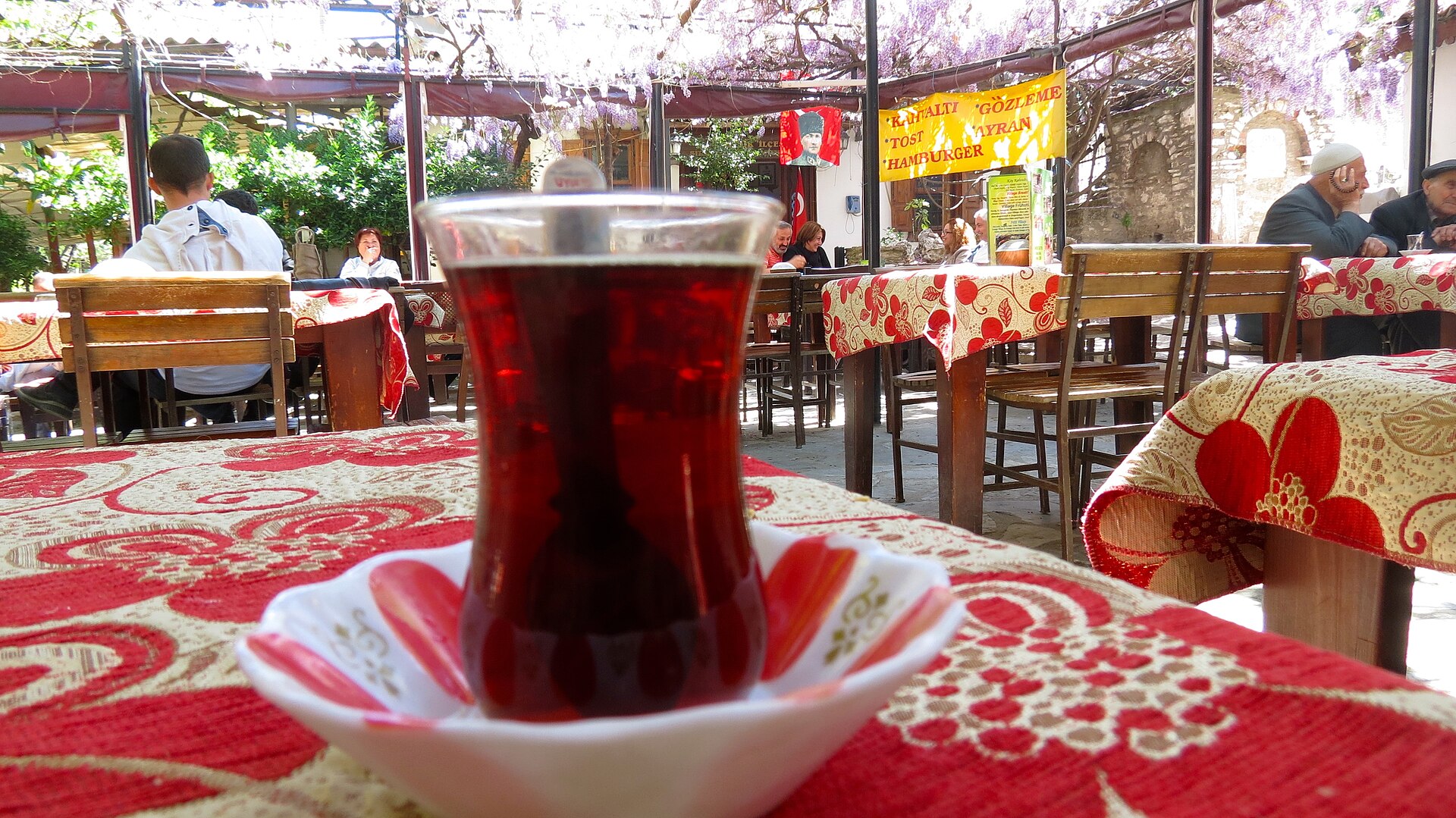 Kırmızı örtülü kahvehane masasında ince belli bardakta demli çay